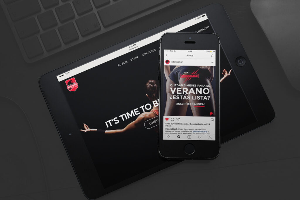 A smartphone displaying a fitness-themed Instagram post rests on a tablet showing a boxing website with the text “ITS TIME TO BOX,” highlighting thoughtful UX and modern design. Both devices are on a dark surface, partially showing a keyboard. - FelipeIgiesias.com
